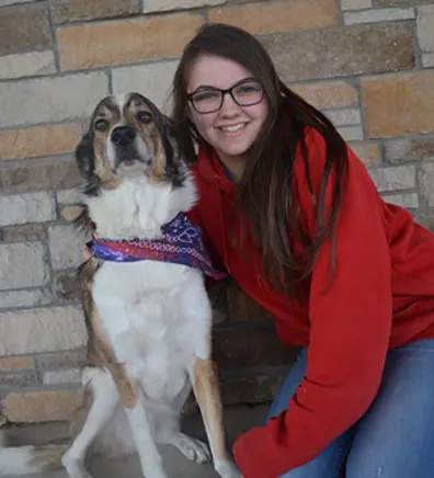 Taylor kneeling down in front of a brick wall next to a white and brown dog wearing a bandana Taylor kneeling down in front of a brick wall next to a white and brown dog wearing a bandana