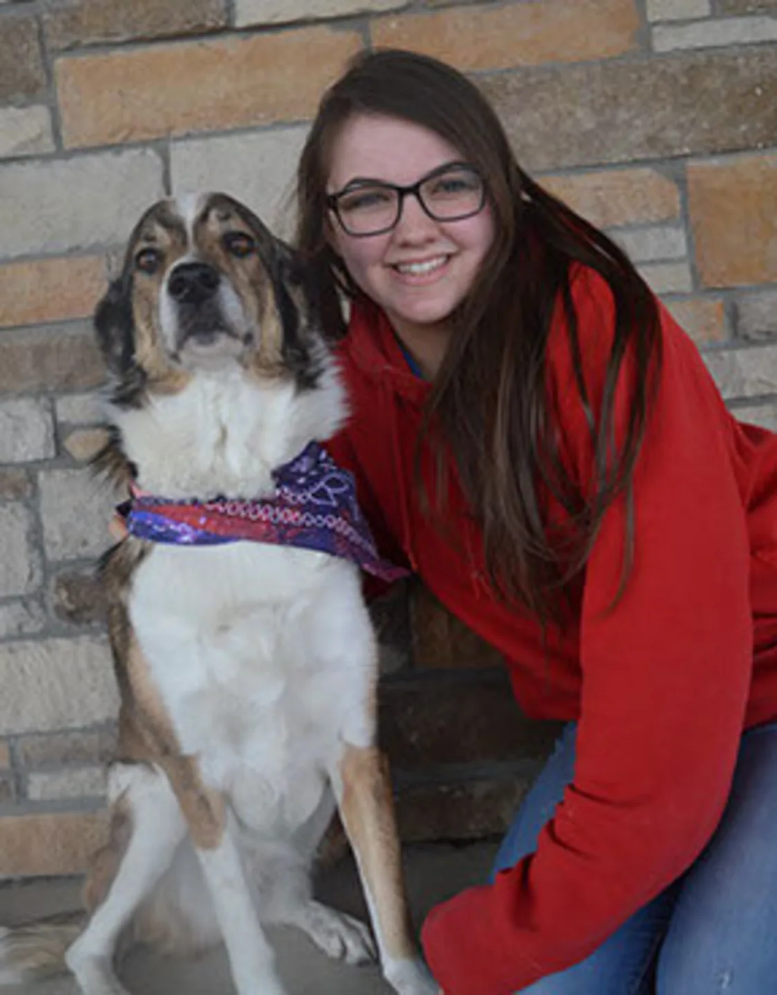 Taylor kneeling down in front of a brick wall next to a white and brown dog wearing a bandana Taylor kneeling down in front of a brick wall next to a white and brown dog wearing a bandana