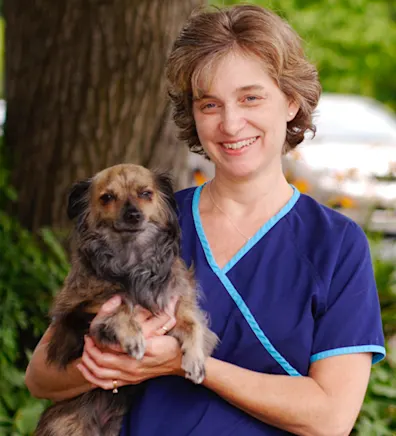 Jennifer standing in front of a tree while holding a dog Jennifer standing in front of a tree while holding a dog