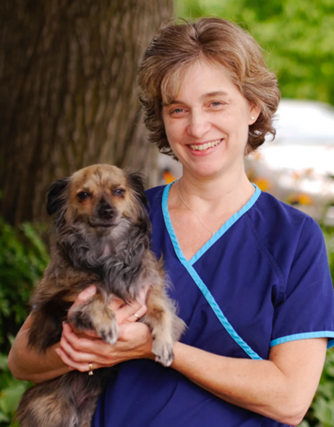 Jennifer standing in front of a tree while holding a dog Jennifer standing in front of a tree while holding a dog