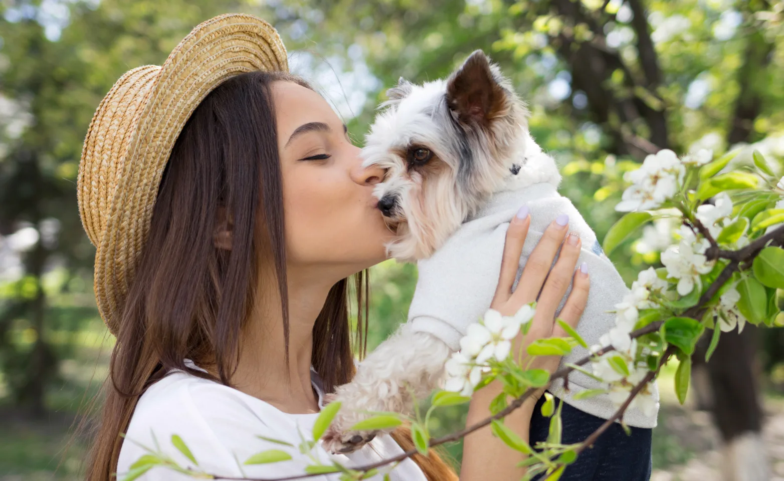 Woman wearing a hat holding up dog