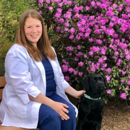 Dr. Kate DeLisle of Northampton Veterinary Clinic sitting on a bench outside while petting a dog