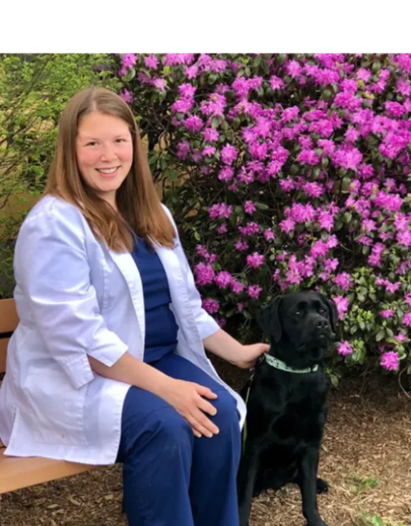 Dr. Kate DeLisle of Northampton Veterinary Clinic sitting on a bench outside while petting a dog