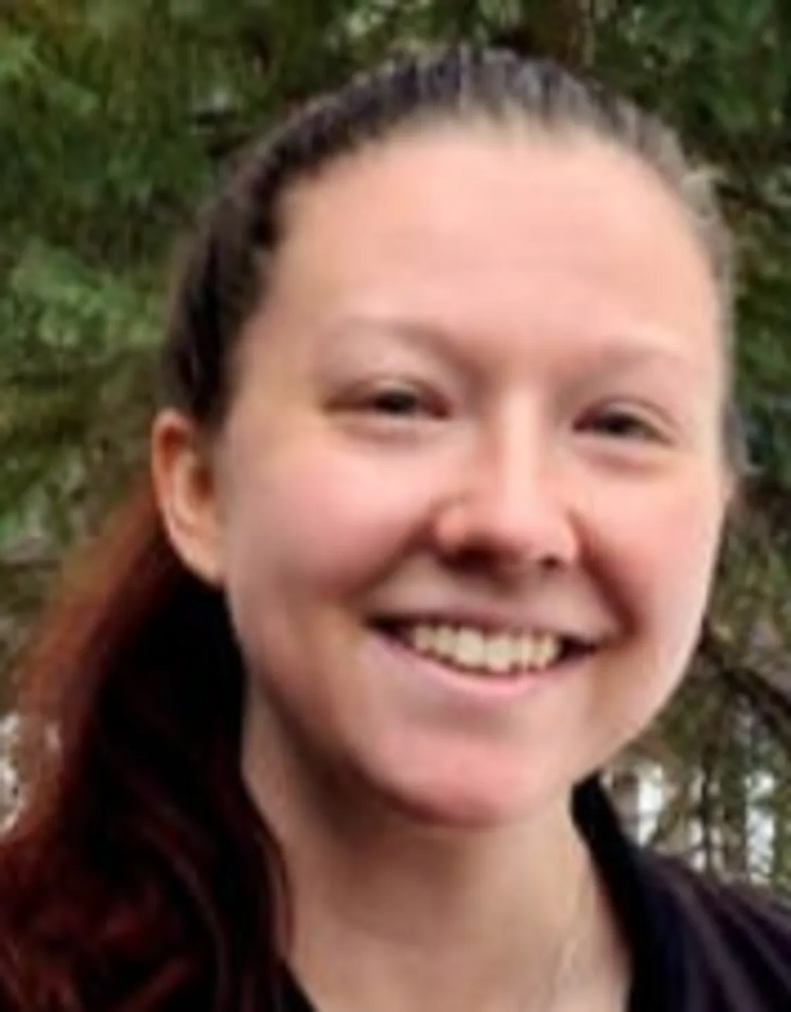 Josee smiling standing outside in front of trees Josee smiling standing outside in front of trees