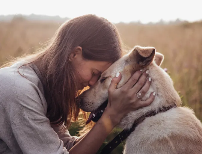 Dog and person with foreheads touching and eyes closed.