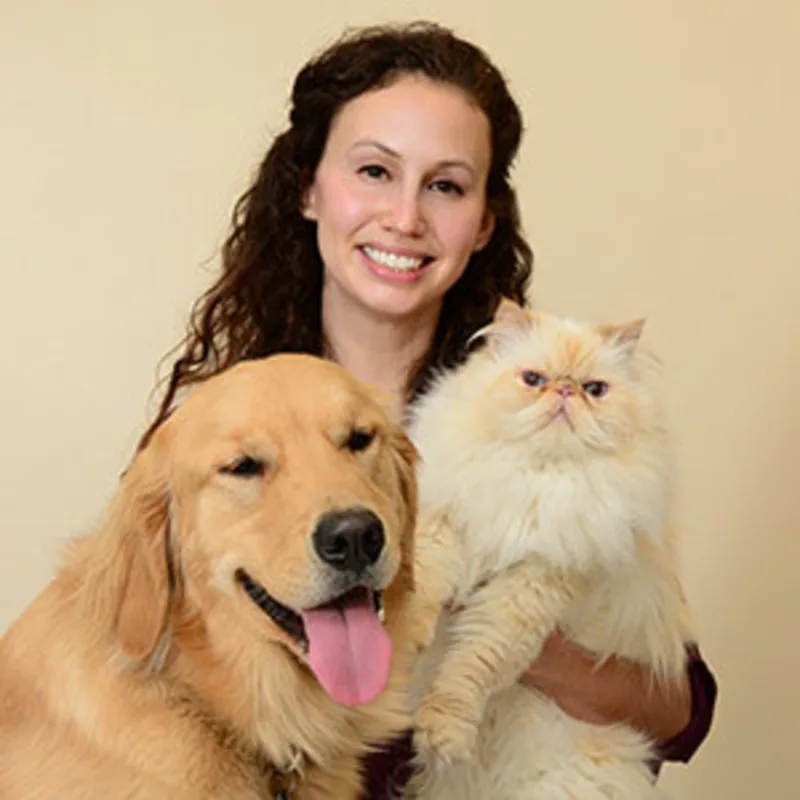 Dr. Ruthie Fliflet's staff photo from Anne Arundel Veterinary Emergency Clinic where she is sitting next to her adult golden retriever and holding her white fluffy cat in one arm. Dr. Ruthie Fliflet's staff photo from Anne Arundel Veterinary Emergency Clinic where she is sitting next to her adult golden retriever and holding her white fluffy cat in one arm.