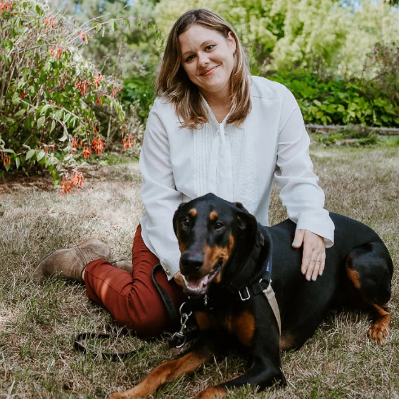 Samantha Peckman sitting on the ground with her black and brown dog Samantha Peckman sitting on the ground with her black and brown dog