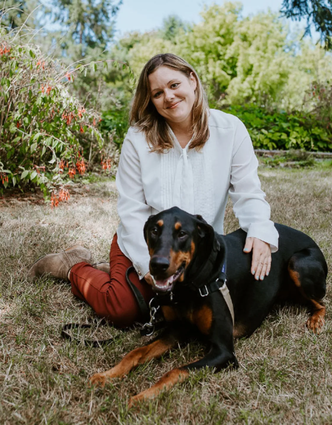 Samantha Peckman sitting on the ground with her black and brown dog Samantha Peckman sitting on the ground with her black and brown dog