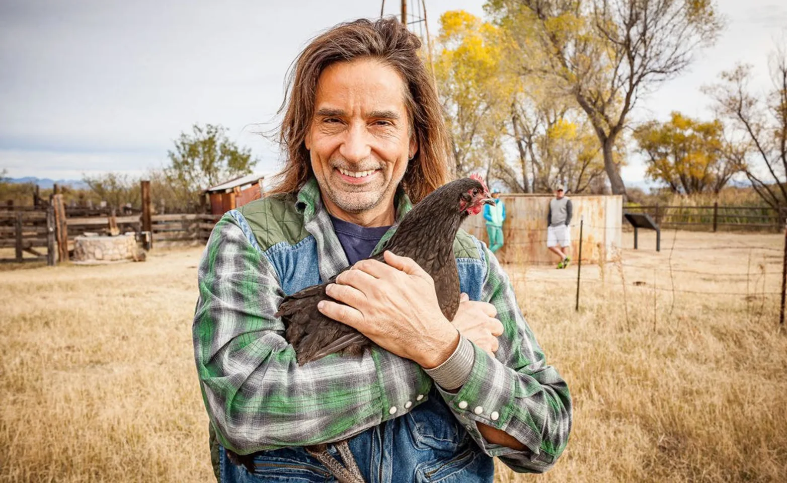 Man in plaid hugging a chicken.