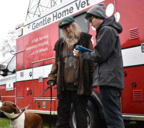 Red Gentle Home Vet truck and 2 men and a dog.