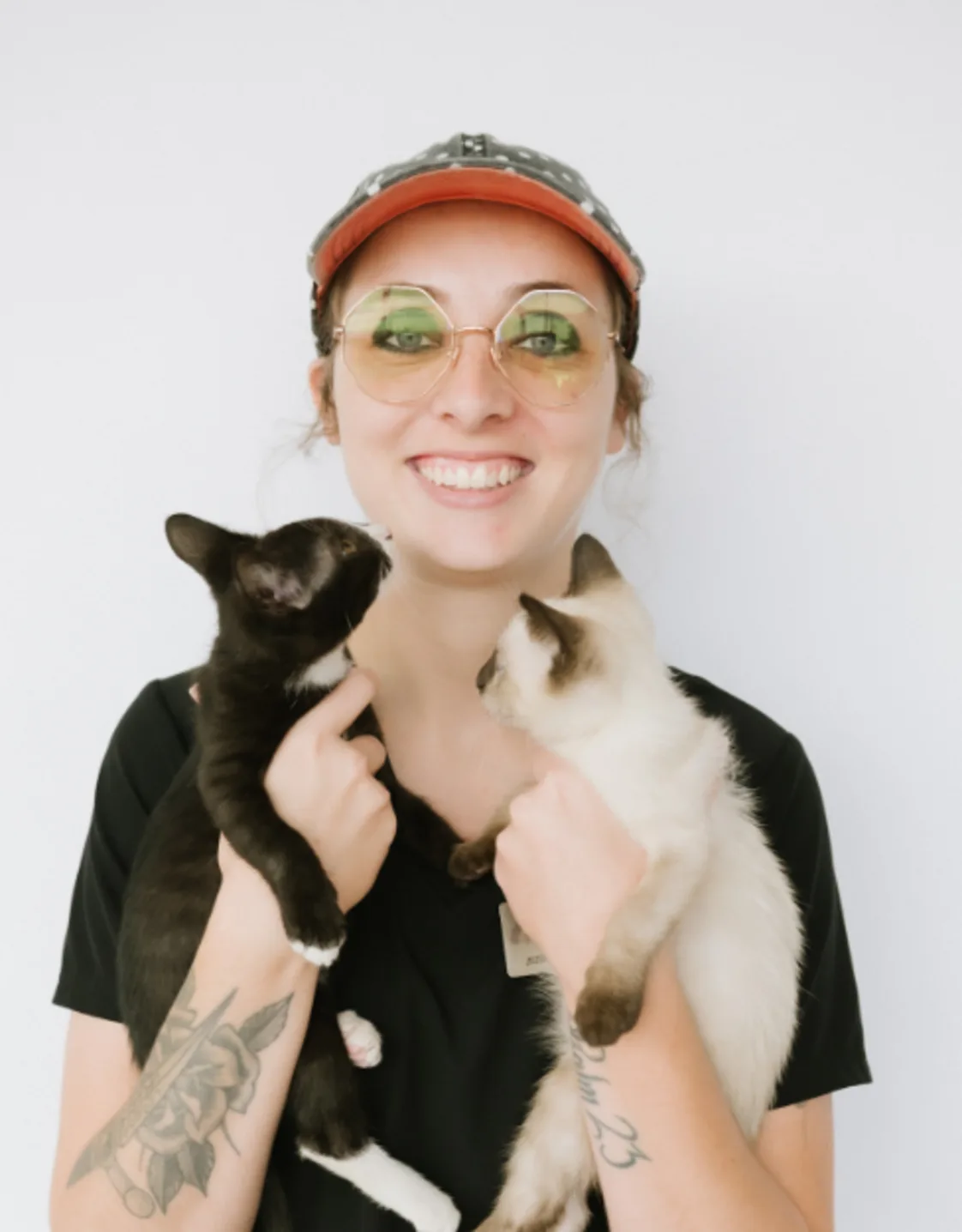 A portrait photo of Kennel Assistant Lauren holding two cats A portrait photo of Kennel Assistant Lauren holding two cats