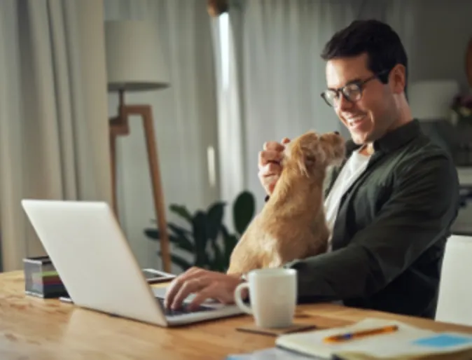 Man sitting with a brown dog while using his laptop at home Man sitting with a brown dog while using his laptop at home