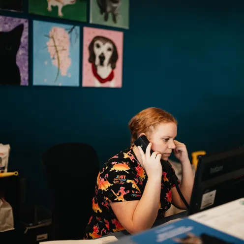 Front desk receptionist on the phone sitting at a desk