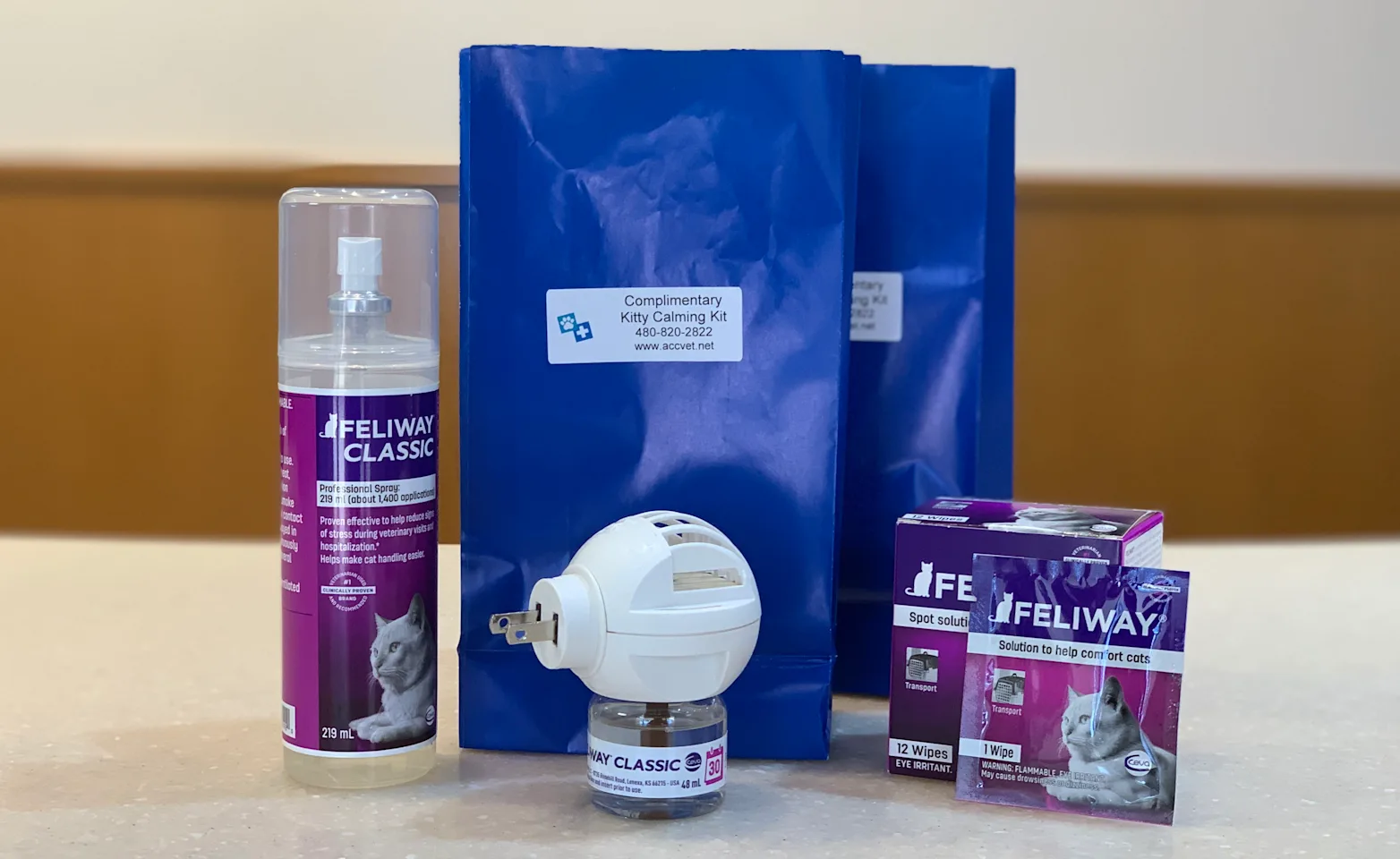 A calming spray, two blue bags, a plug-in scent diffuser, and a box on a table. A calming spray, two blue bags, a plug-in scent diffuser, and a box on a table.