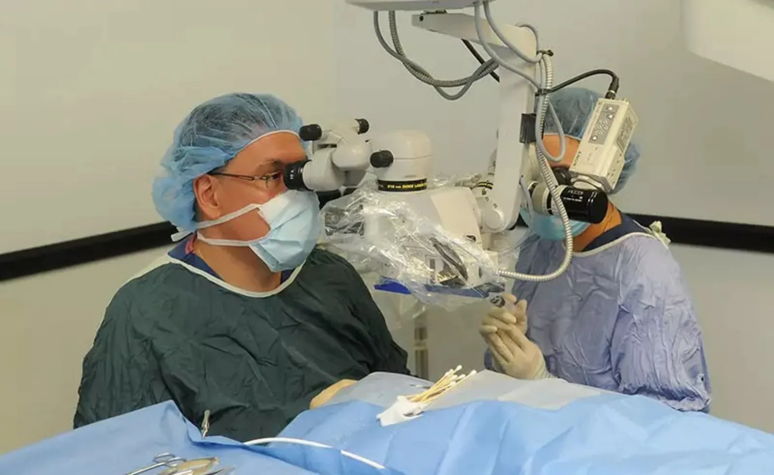 Ophthalmologists performing a procedure while getting a closer inspection with medical equipment. Ophthalmologists performing a procedure while getting a closer inspection with medical equipment.