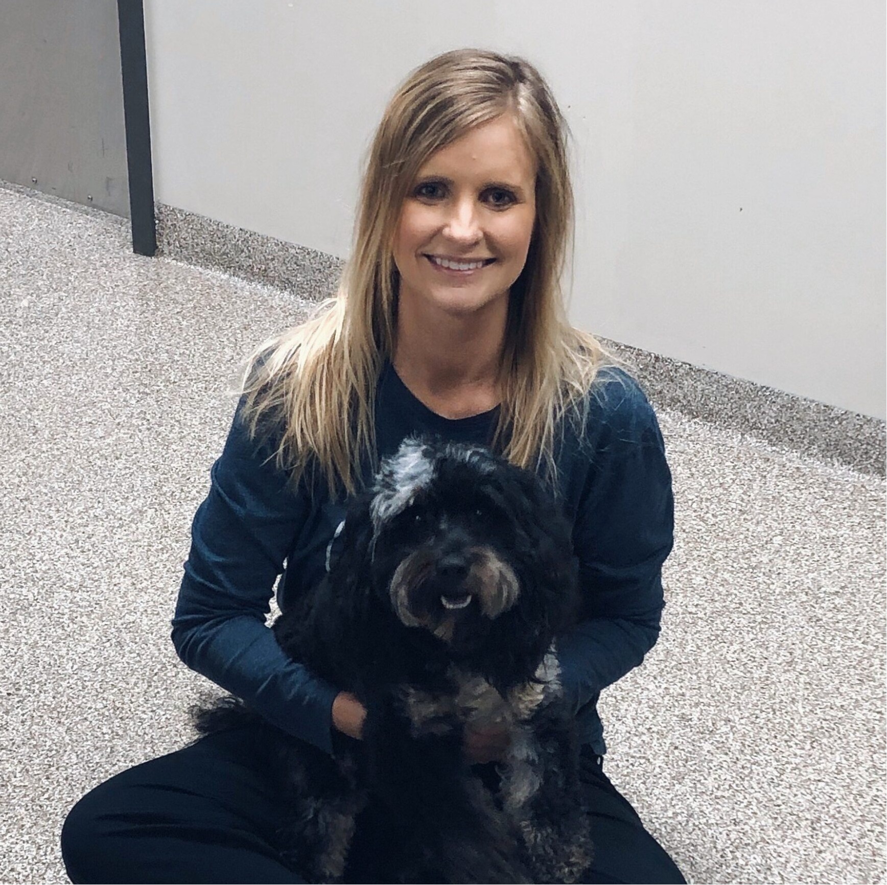 A veterinarian posing with a black dog 