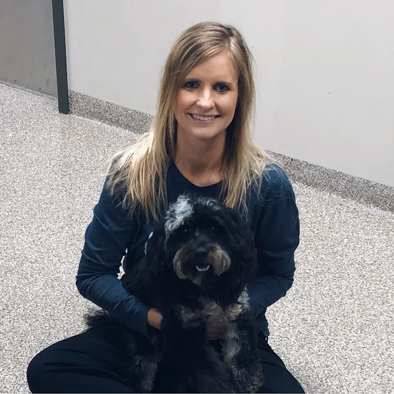 A veterinarian posing with a black dog A veterinarian posing with a black dog