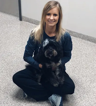 A veterinarian posing with a black dog A veterinarian posing with a black dog