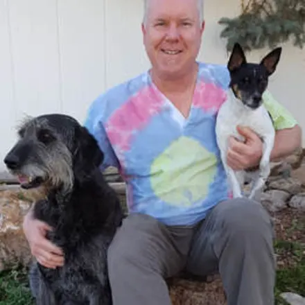 Dr. Jon McCormick sitting outside while holding two dogs