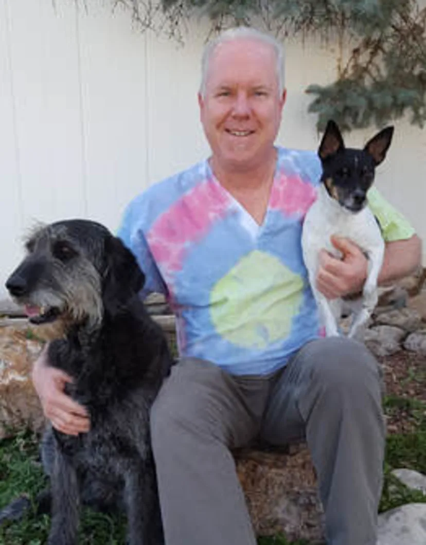 Dr. Jon McCormick sitting outside while holding two dogs