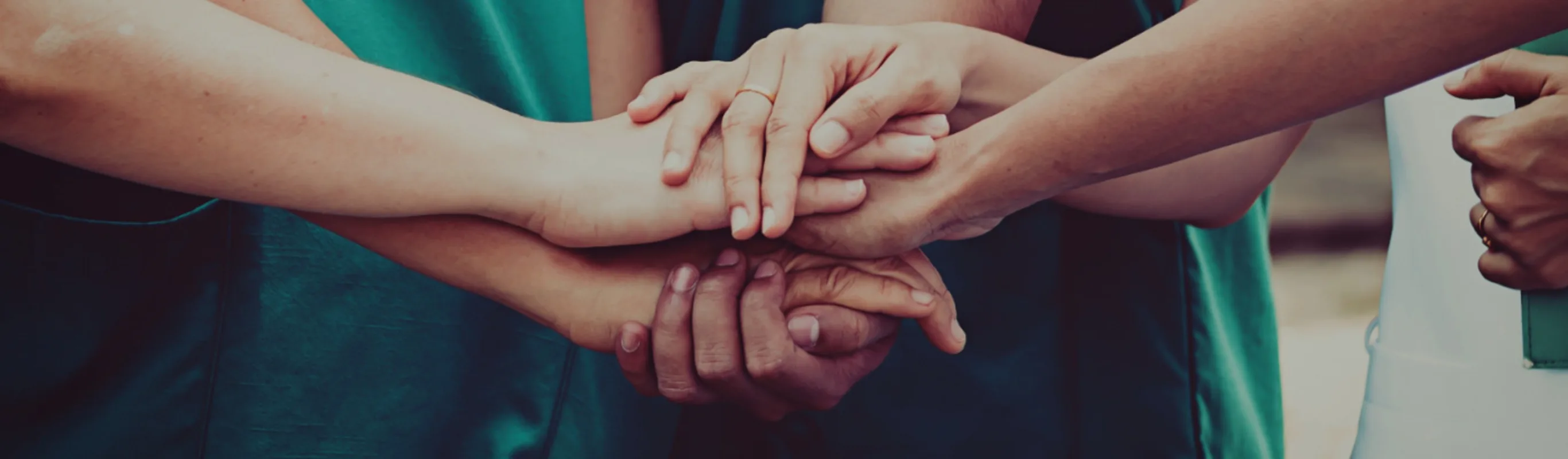 A group of individuals holding hands in the center of the group. A group of individuals holding hands in the center of the group.