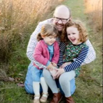 Dr. Chris Eaton's staff photo with his two daughters onutside in a green field.