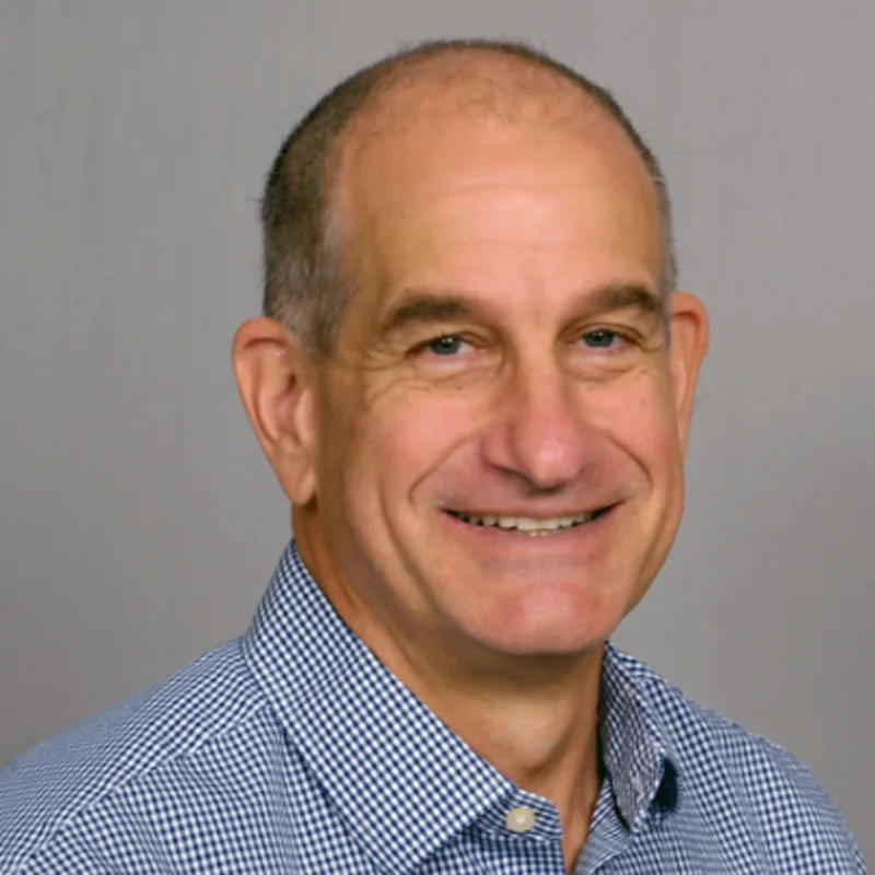 Sean Aiken smiling in front of a grey wall Sean Aiken smiling in front of a grey wall
