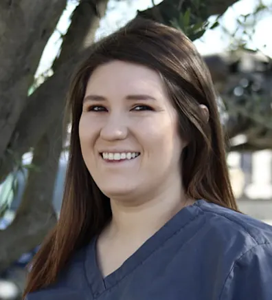 Woman wearing blue scrubs smiling at the camera Woman wearing blue scrubs smiling at the camera