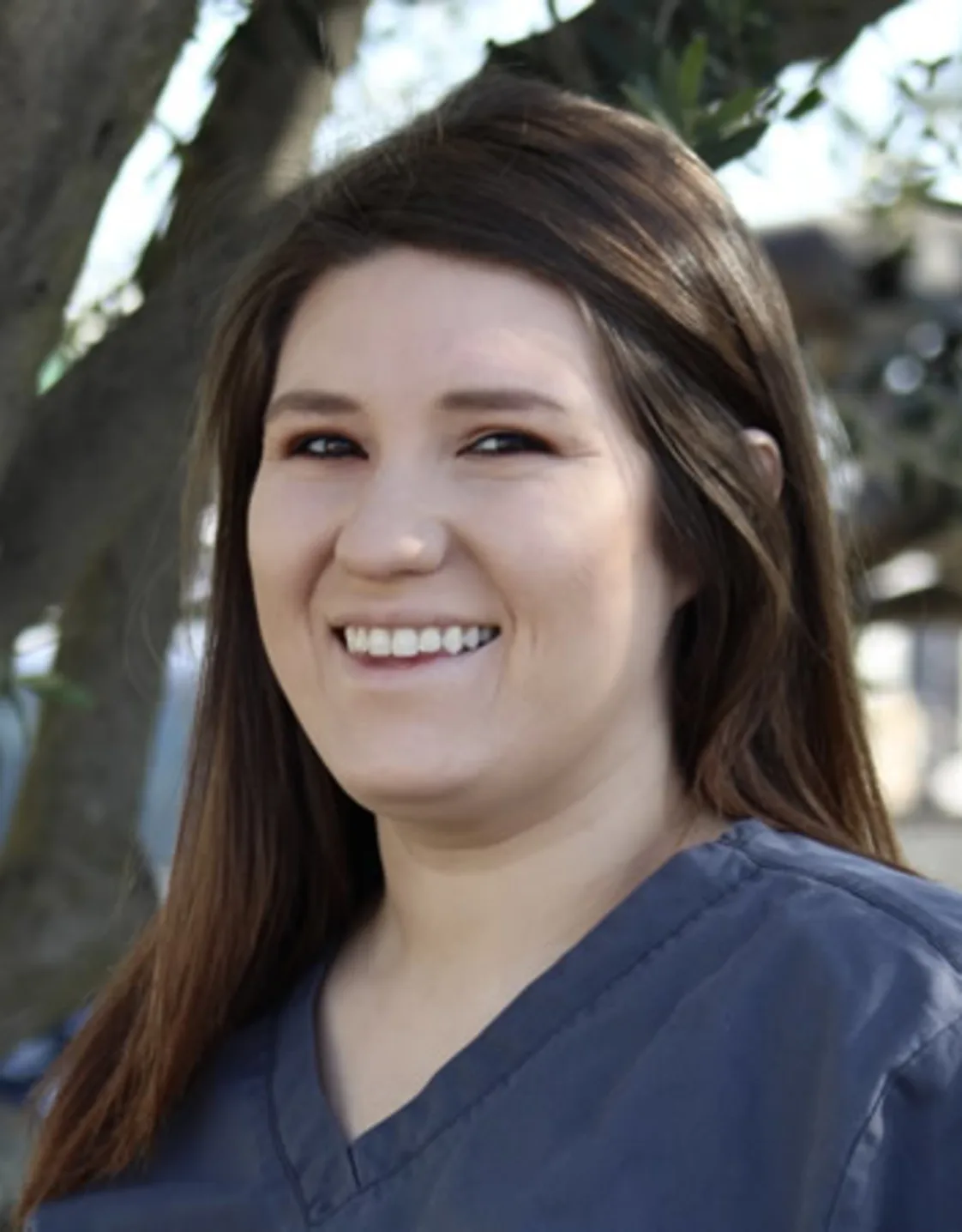 Woman wearing blue scrubs smiling at the camera Woman wearing blue scrubs smiling at the camera