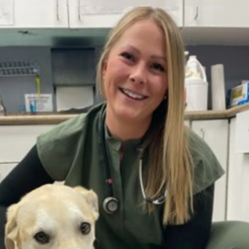 Dr. Jen Johnston kneeling next to a dog Dr. Jen Johnston kneeling next to a dog