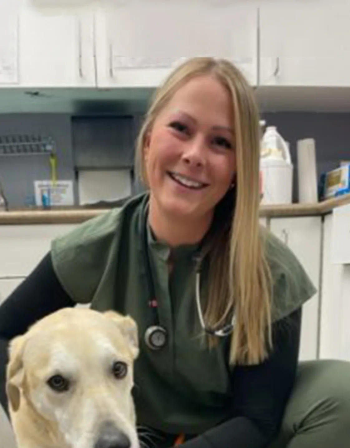 Dr. Jen Johnston kneeling next to a dog Dr. Jen Johnston kneeling next to a dog