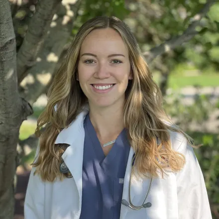 Dr. Morgan Murray standing in front of a tree wearing a white lab coat