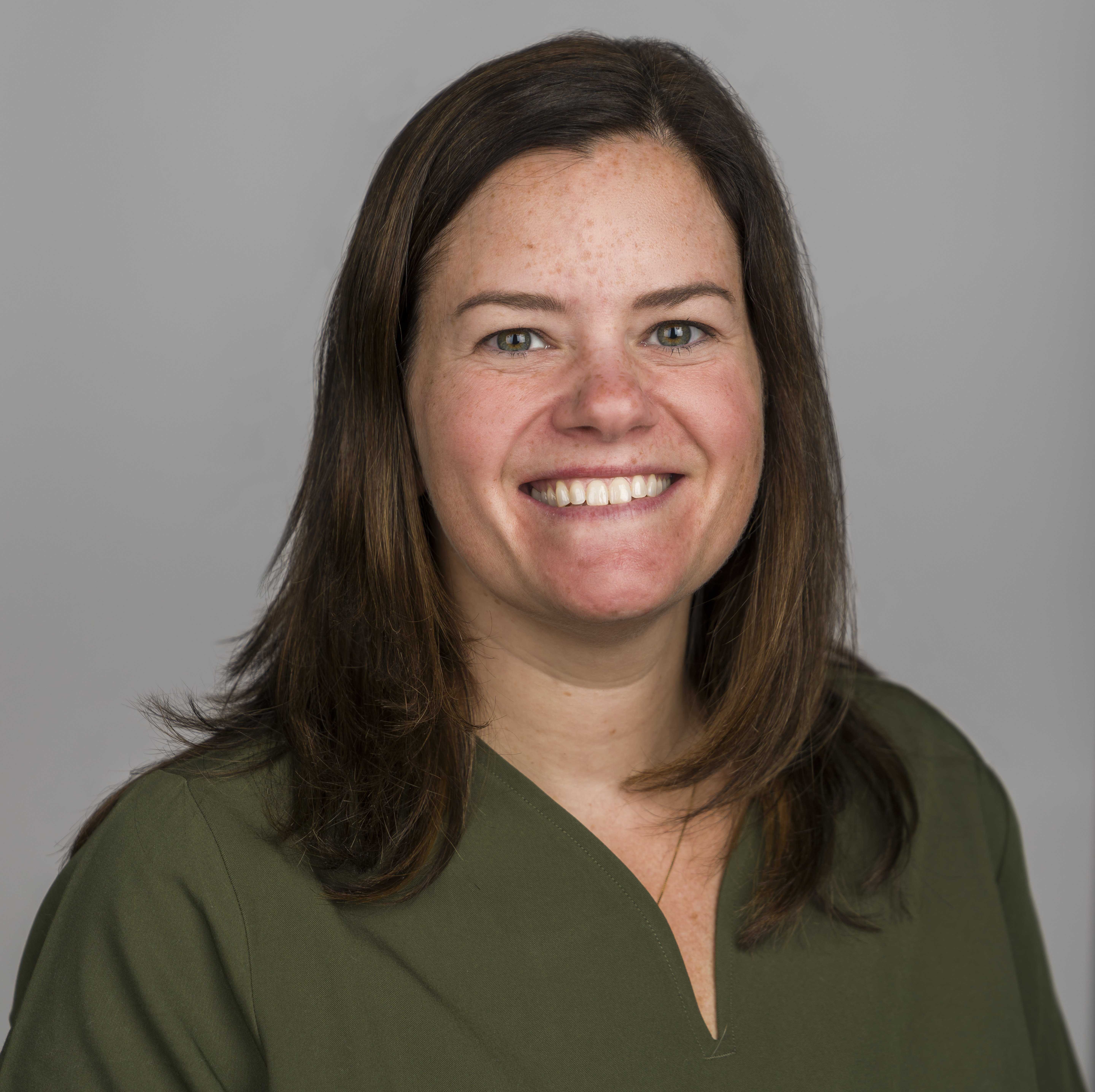 A photo of Dr. Thompson smiling in front of some trees