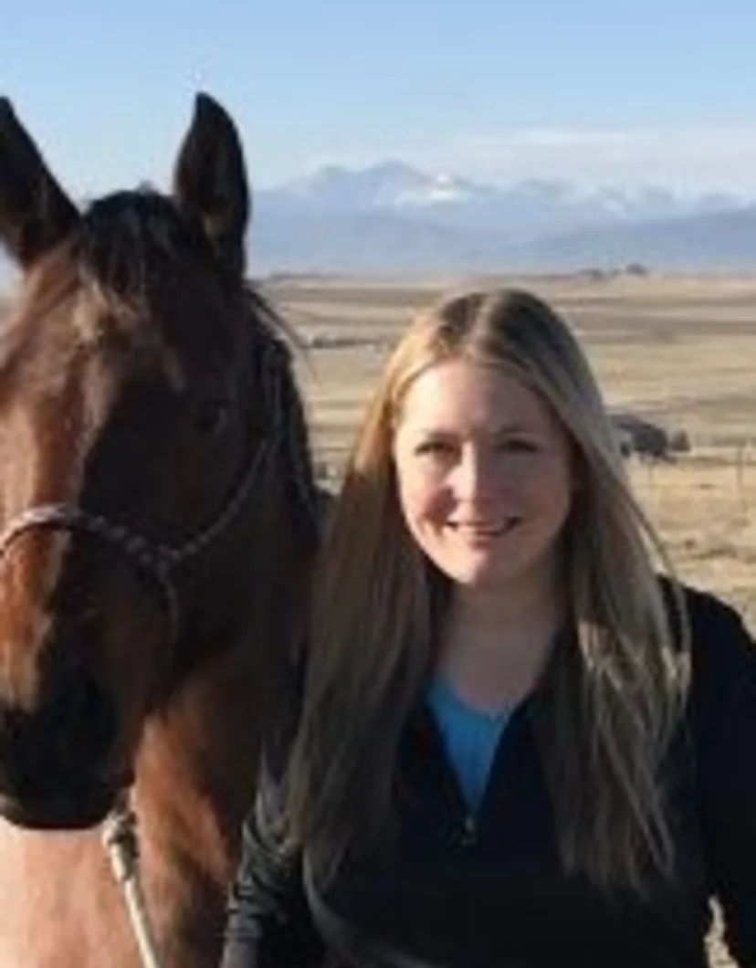 Dr. Jessica Wydallis standing outside with a brown horse