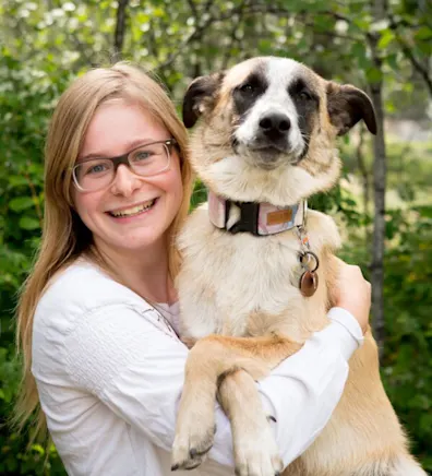 Keira holding a tan, white, and black dog in her arms