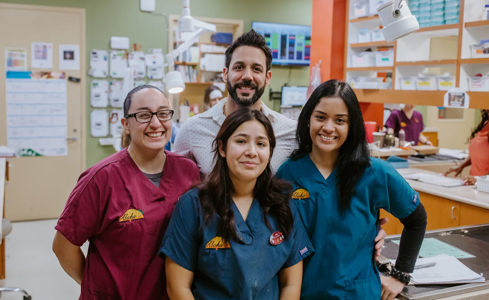 A team of four veterinary professionals standing in the treatment area and smiling A team of four veterinary professionals standing in the treatment area and smiling