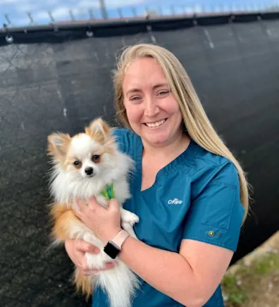 Alex Rominger holding a small fluffy dog