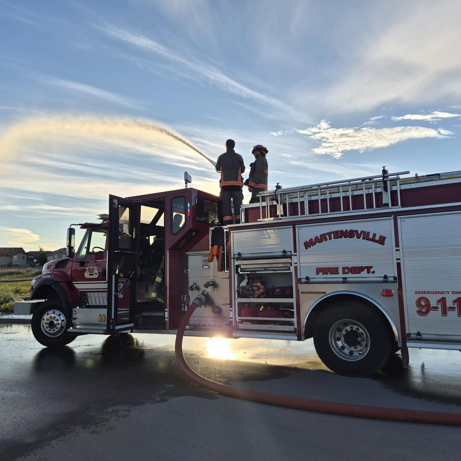 Firefighters standing on the top of a firetruck.
