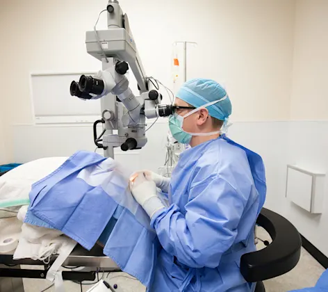 surgeon looking through a microscope surgeon looking through a microscope