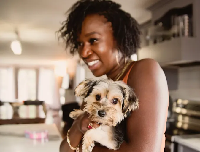 Woman holding a small dog in her home Woman holding a small dog in her home