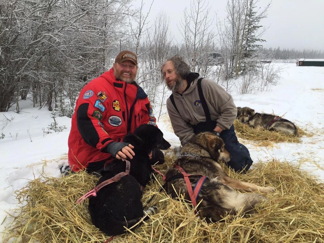 2 staff outside in snow with dogs