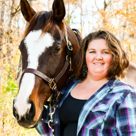 Katy Merritt with a horse and smiling at the camera