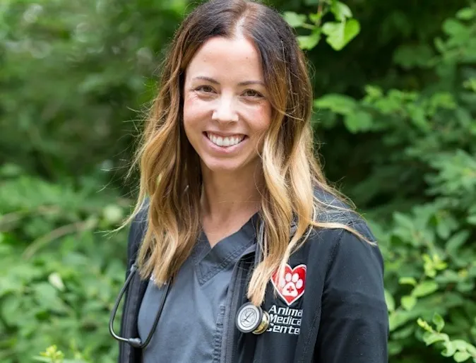 Dr. Kasey Aona smiling at the camera while holding a kitten