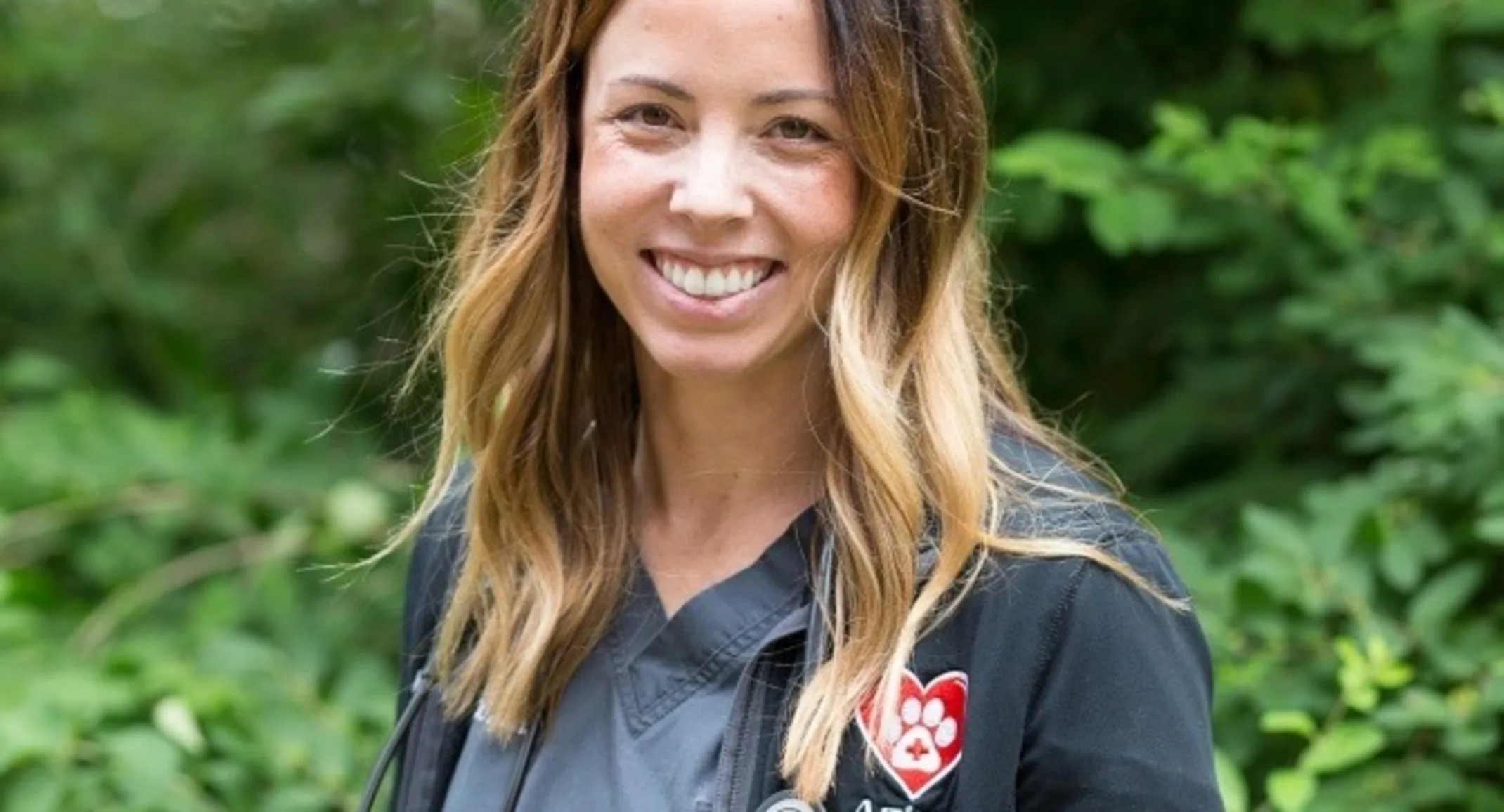 Dr. Kasey Aona smiling at the camera while holding a kitten