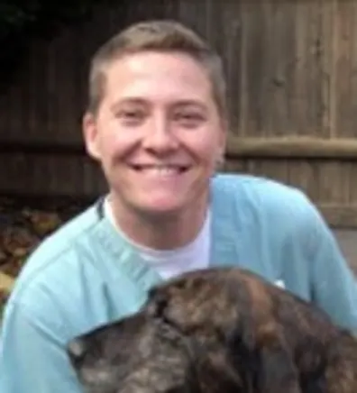 Kim sitting in front a fence while holding a dog Kim sitting in front a fence while holding a dog