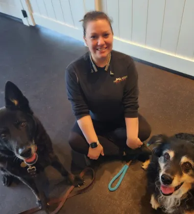 Amanda, trainer at No Leash Needed Rock Hill, sitting on the floor with two dogs