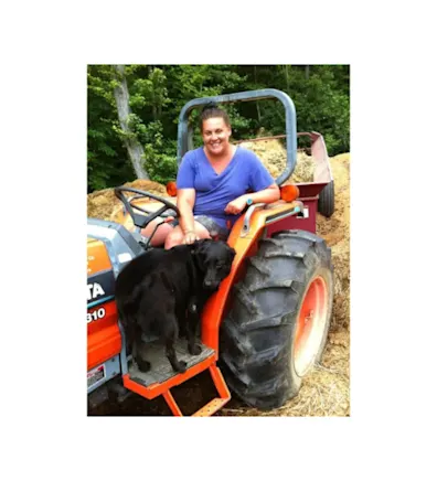 A photo of Lindsay on a tractor with their dog