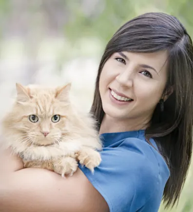 Nikki dressed in blue scrubs holding an orange cat