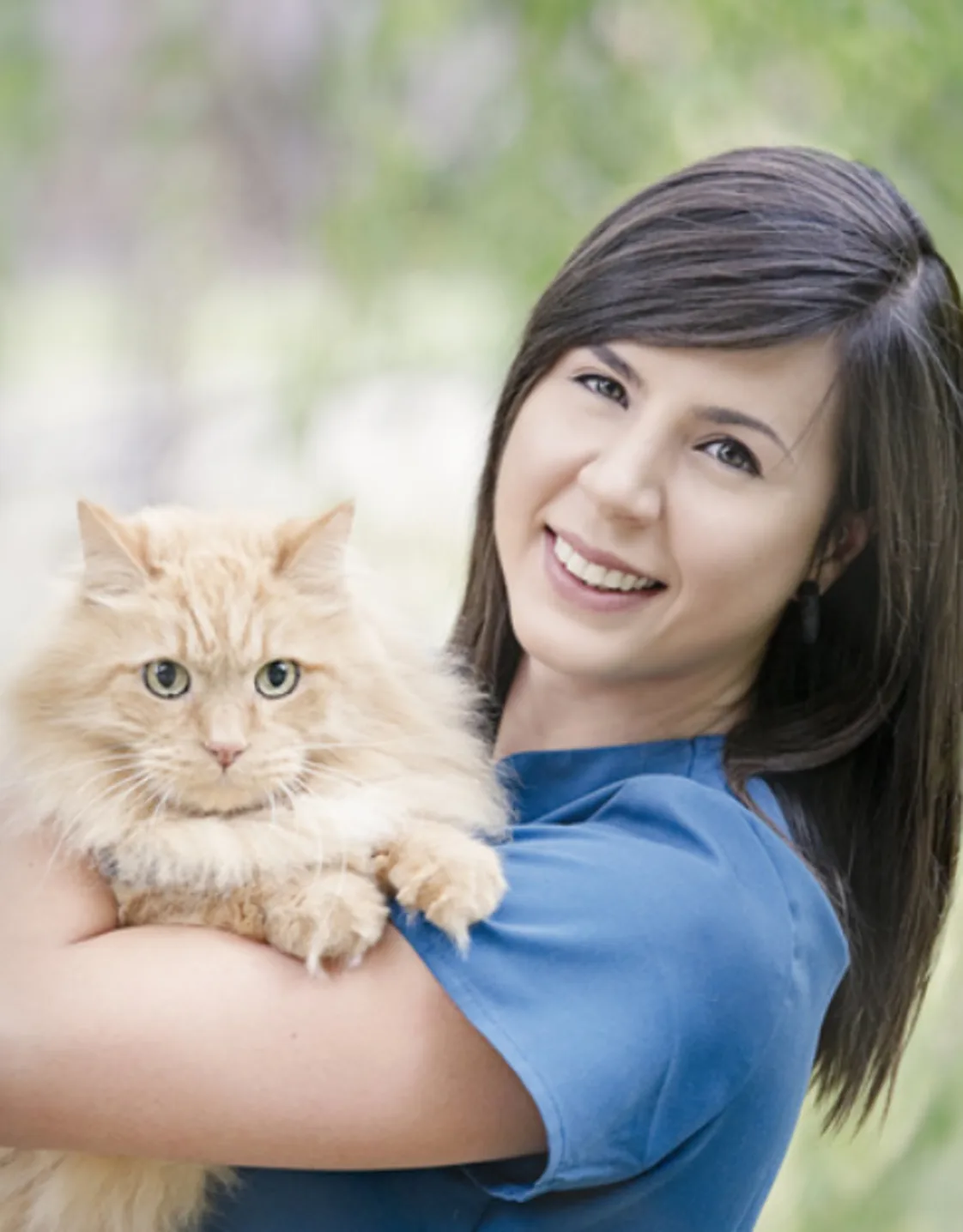 Nikki dressed in blue scrubs holding an orange cat Nikki dressed in blue scrubs holding an orange cat