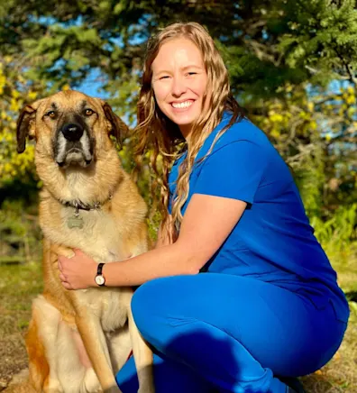 Ana in blue scrubs sitting next to a large dog. Ana in blue scrubs sitting next to a large dog.